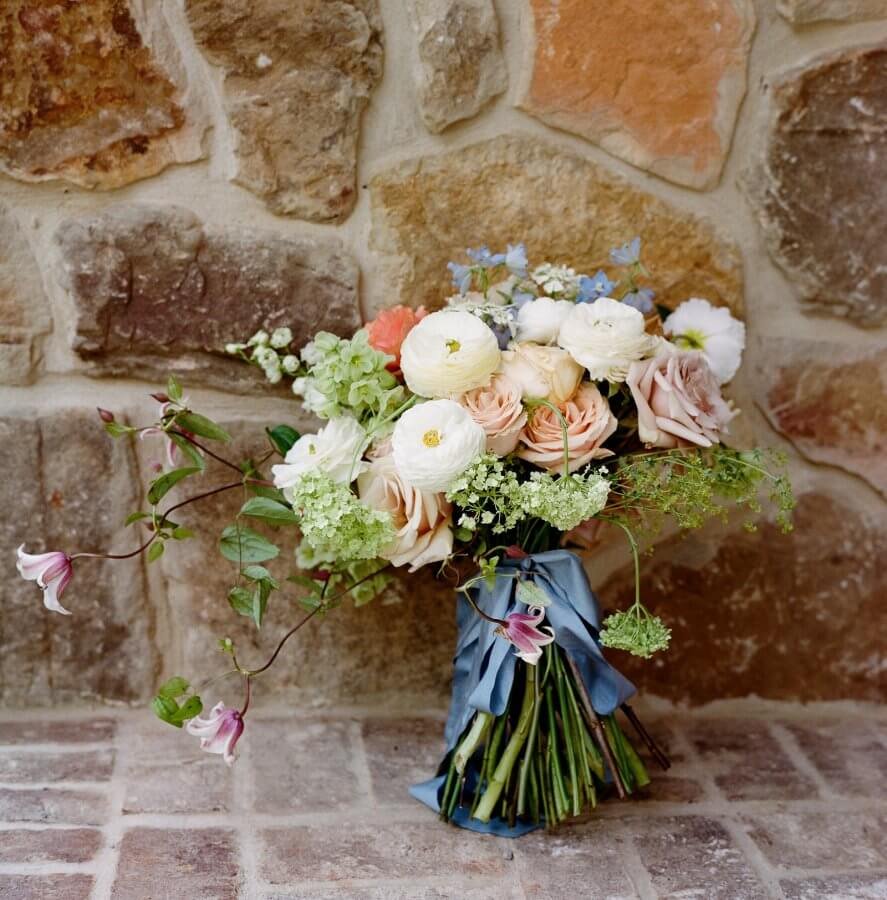 The bride's floral bouquet tied with blue ribbon.