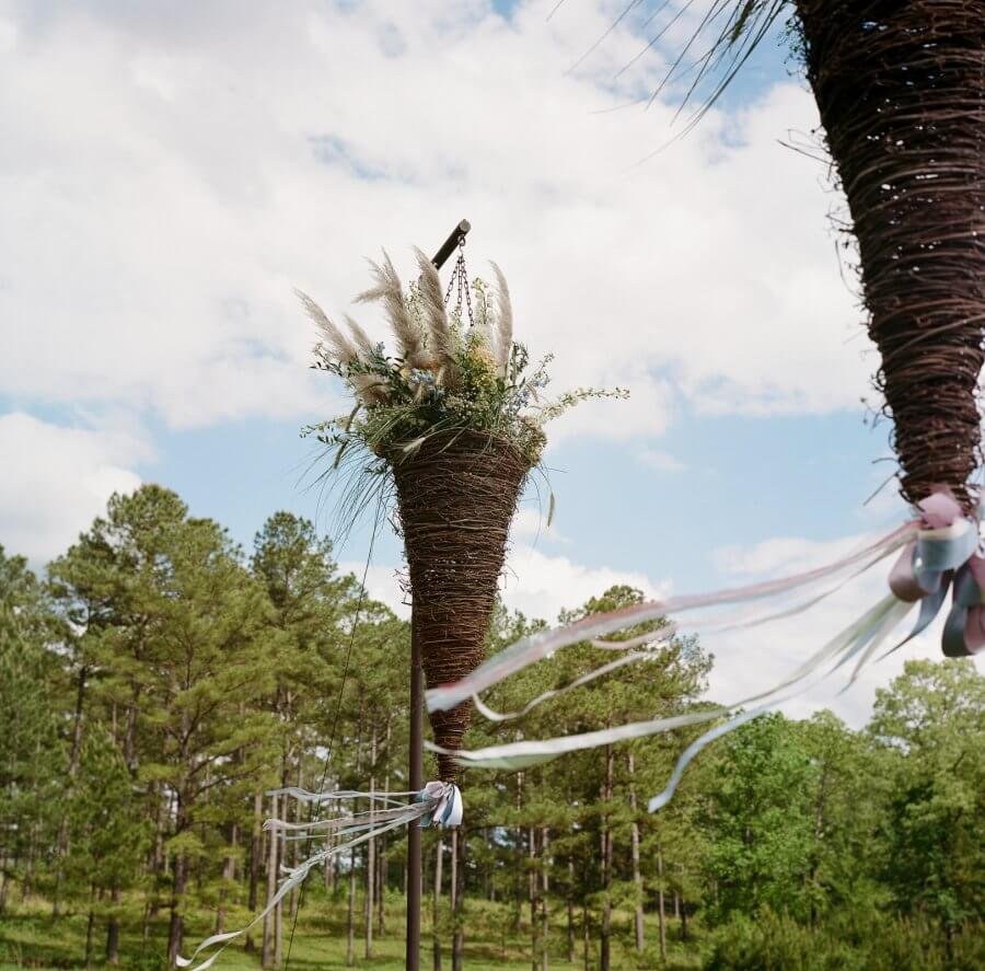 Twig cones line the wedding aisle with flowers and ribbons